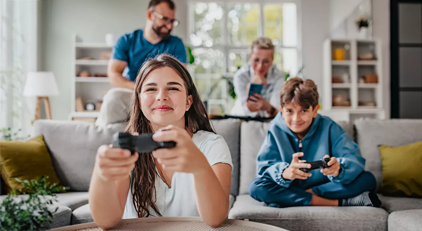 Siblings gaming while parents use phones in the background